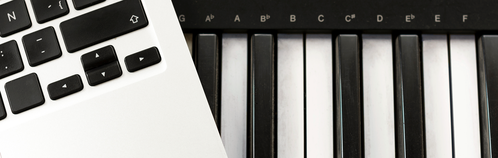 flatlay of computer keyboard on top of digital piano keyboard