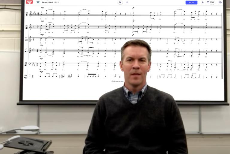Keith Ozsvath sitting in front of a smartboard with Sight Reading Factory being displayed on it