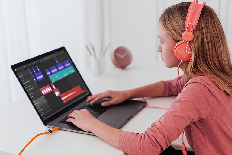 Girl looking at Soundation Education on a laptop while wearing headphones