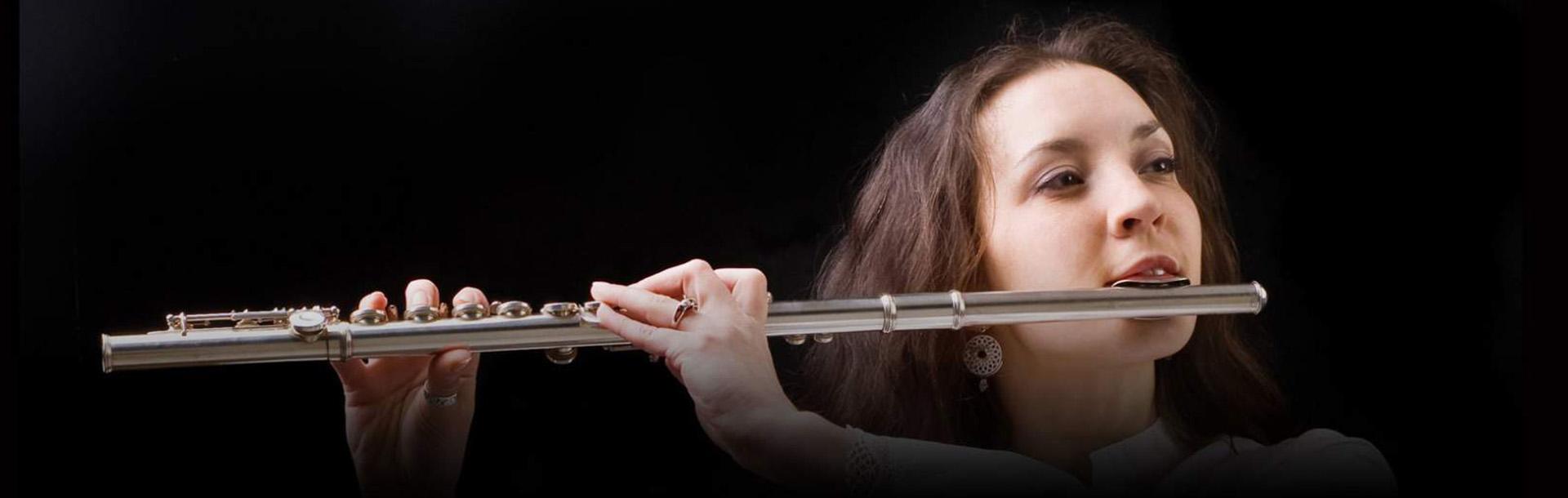 woman playing the flute in front of a black background
